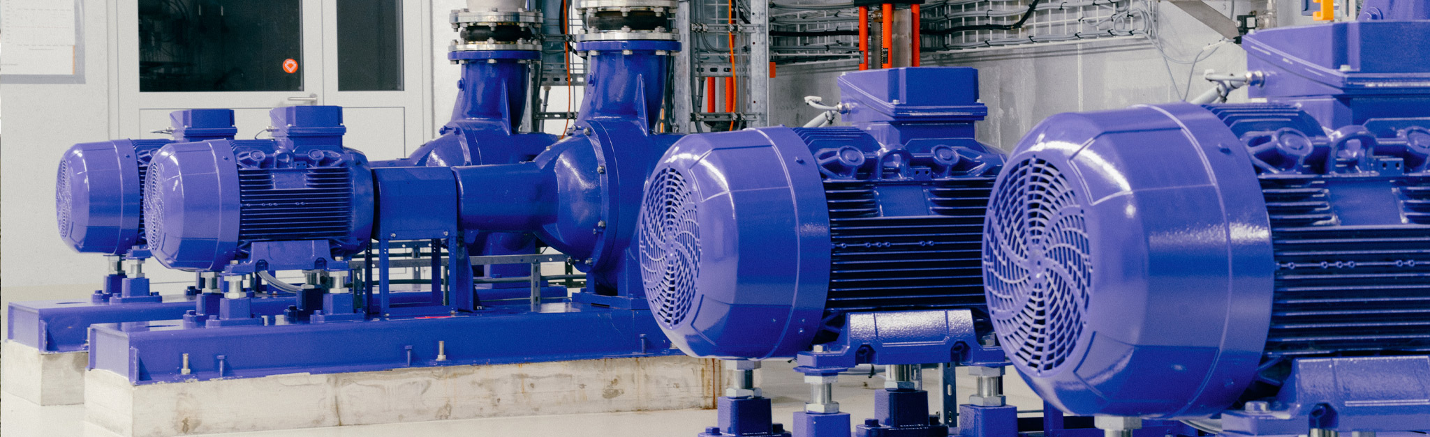 Eine Gruppe blauer Industriepumpen in einem Raum.